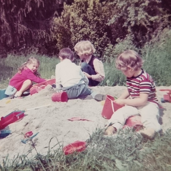 vier Kinder spielen im Sand.